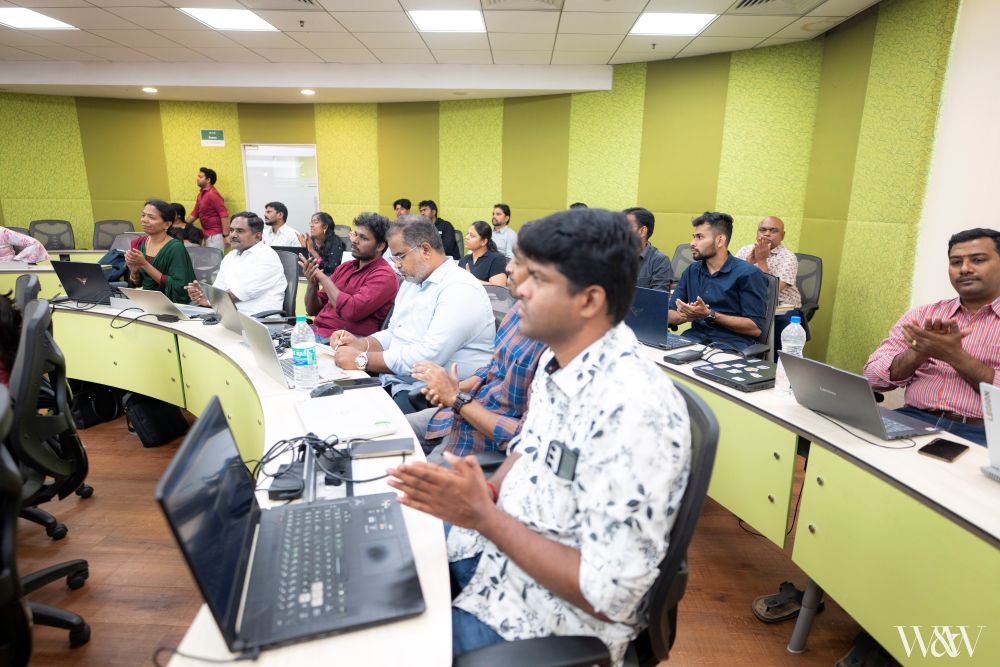 Three men collaborating around laptop in classroom