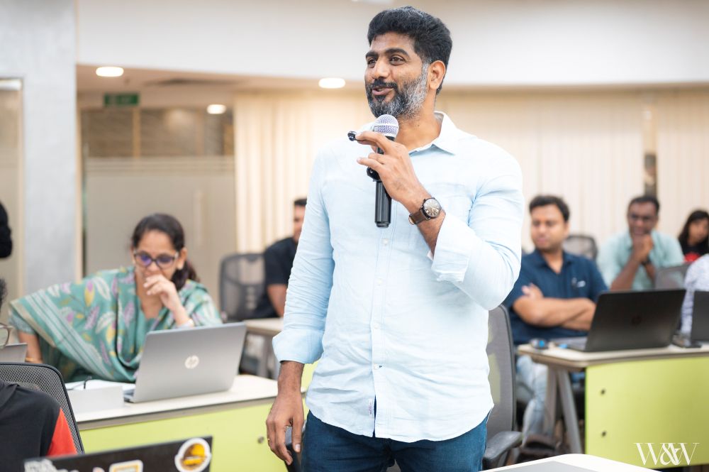Young man in white polo presenting at podium with microphone
